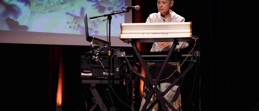 Artist behind keyboard in front of projection