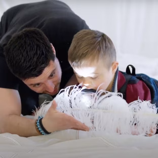 A baby looking at a feather in a white tent